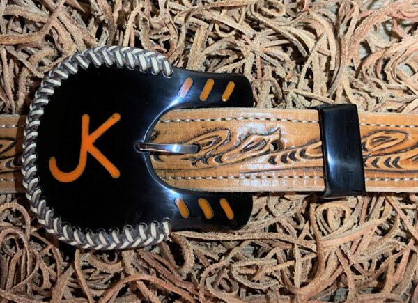 a dark cow horn buckle with inlay, braid, and tracks.