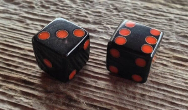 a dark pair of dice with red dots