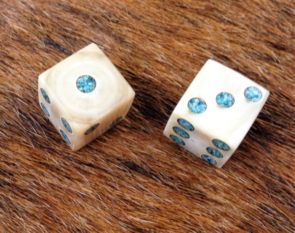 a set of cow horn dice with turquoise dots