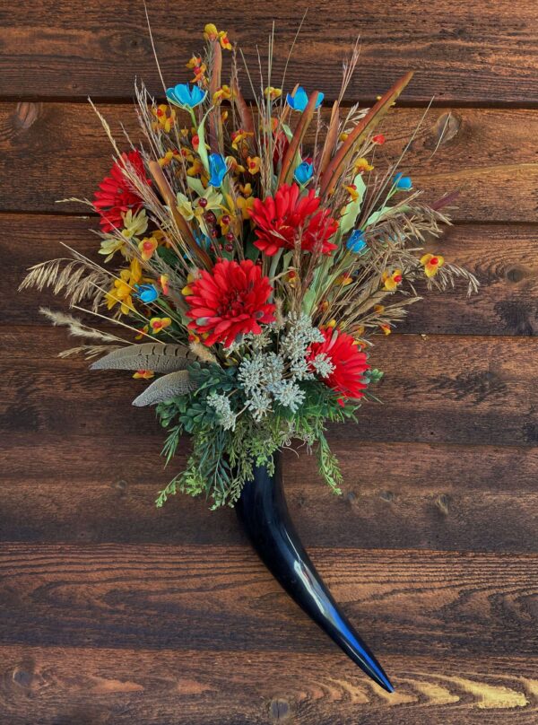 a flower arrangement with a darker cow horn vase