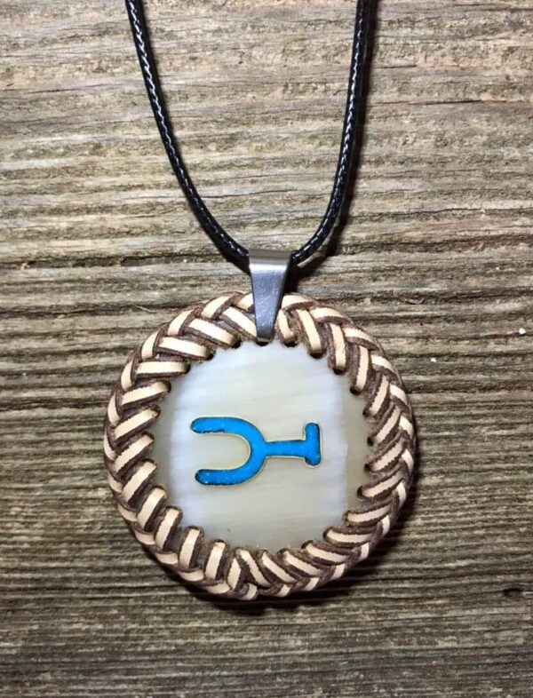 a cow horn round pendant with turquoise inlay and braid