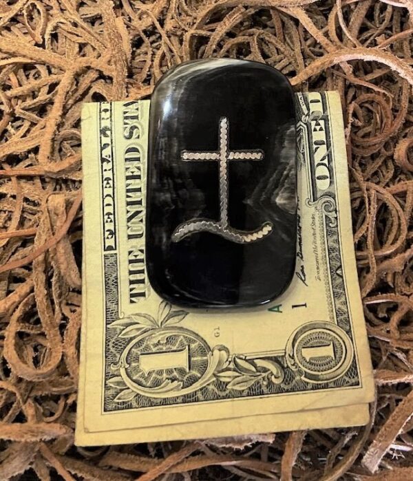 a dark color cow horn money clip with inlay holding one dollar.